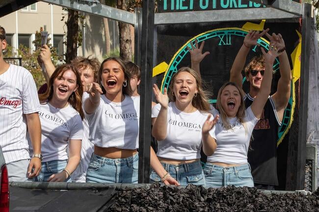 Alpha Chi Omega sorority girls cheer from their perch atop a 2023 Homecoming Parade float